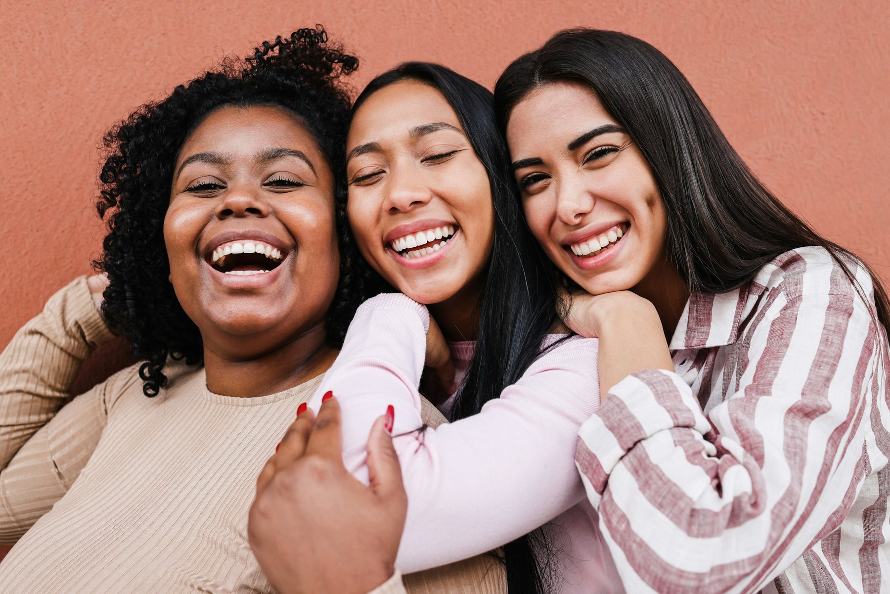 Três amigas abraçadas a rir